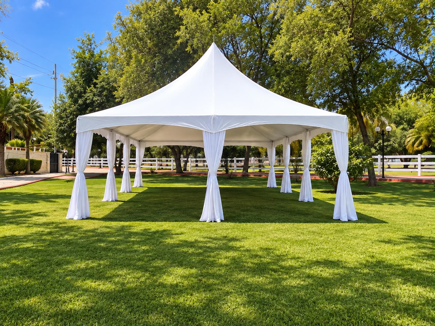 Carpa de punta blanca instalada en jardín amplio